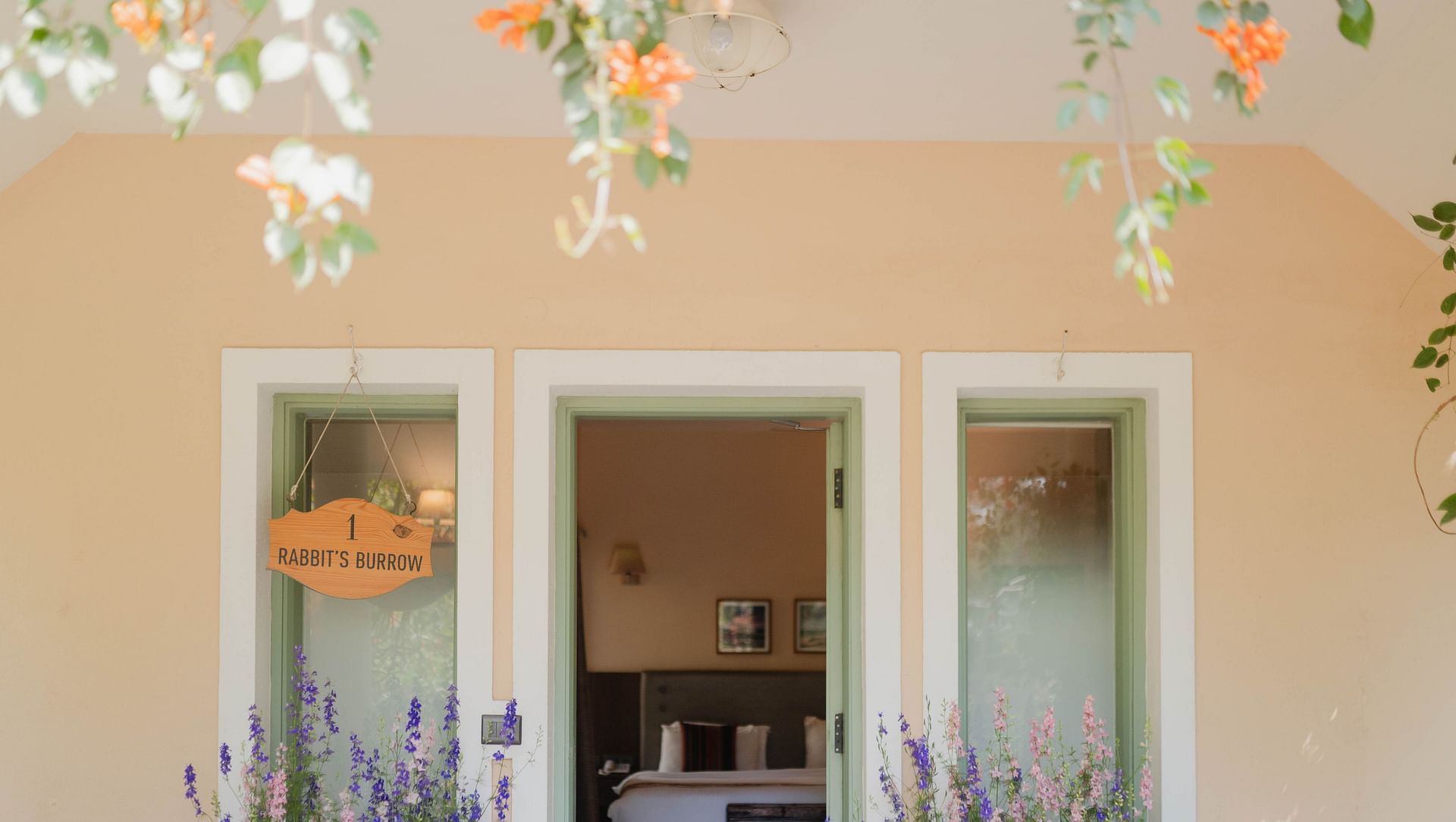 Exterior view of a Karma Chalets unit with two doors, potted plants, and hanging decor.