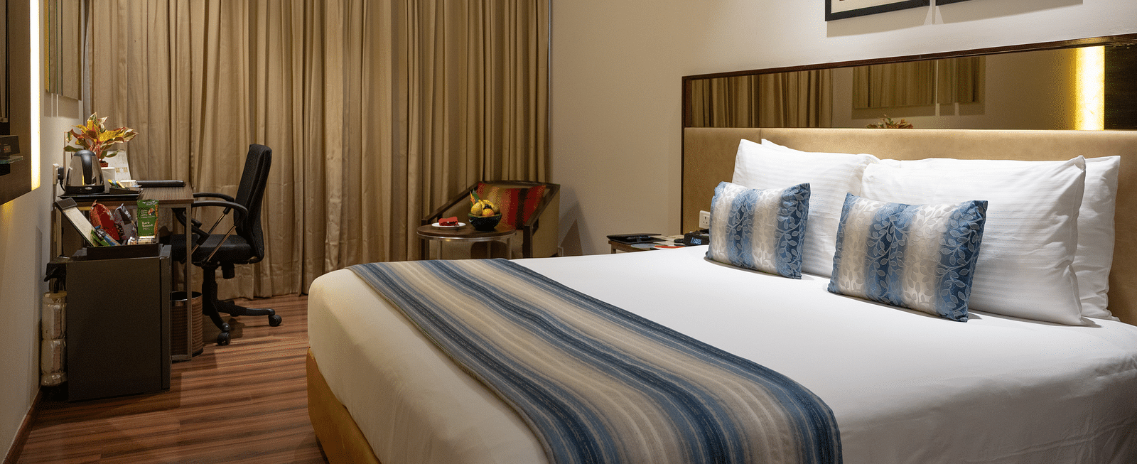 An image of one of the hotel rooms in Kakinada with working table and a chair at long shot view of the hotel corridors at Grand Kakinada by GRT Hotels