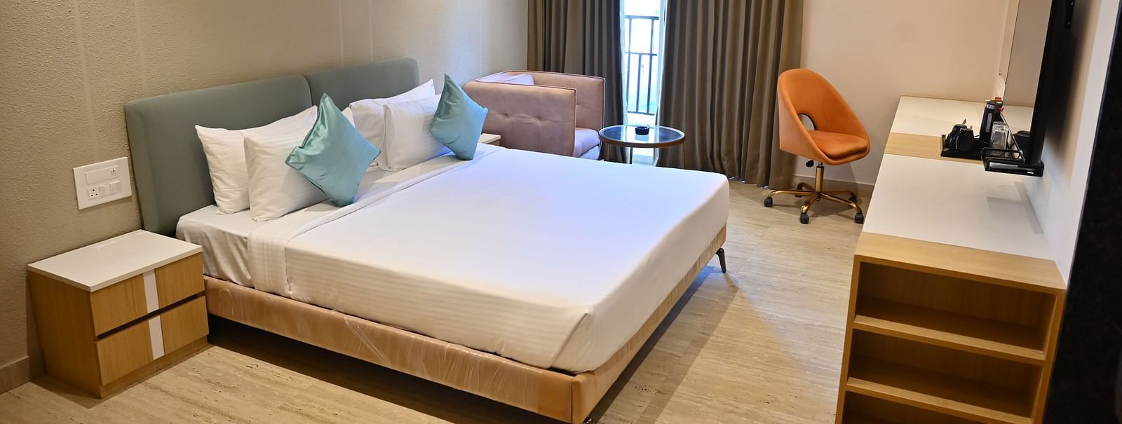 Bright and airy premium room with a big bed, soft chairs, and curtains over large windows, offering plenty of light and modern features at TGI Livancia Hillside