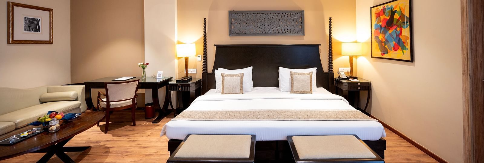 Presidential suite bedroom at Essentia Luxury Resort & Spa, Udaipur, featuring a neatly made bed, a side sofa seater, a coffee table, and modern interior decor