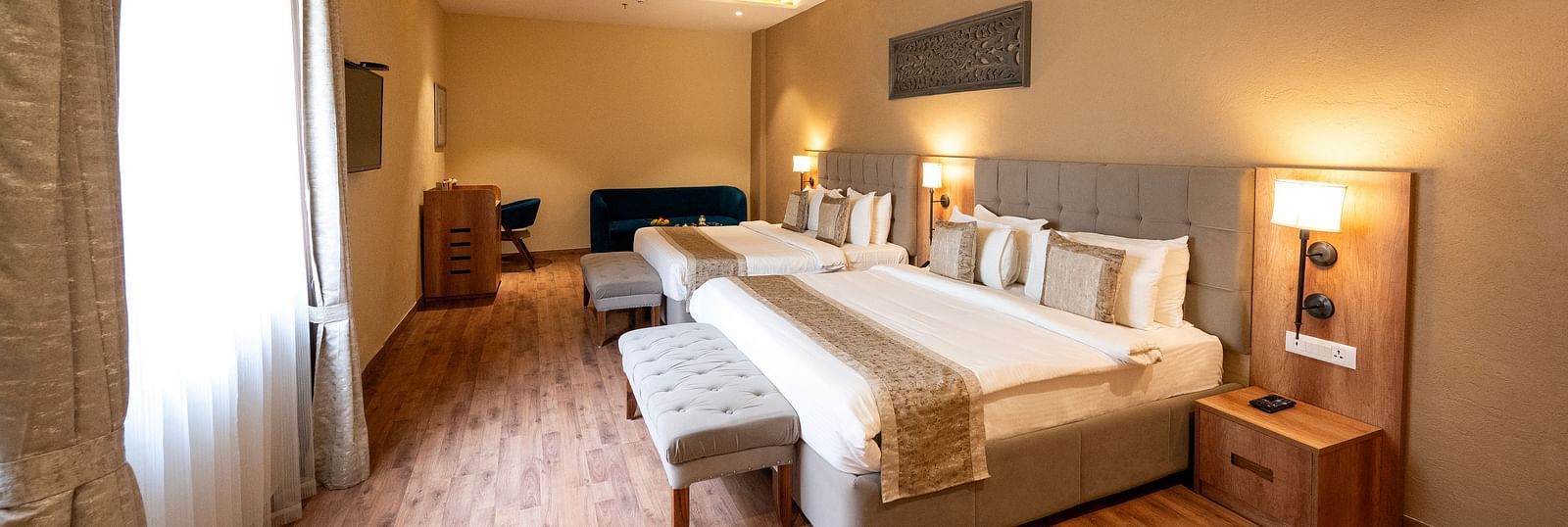 Studio quad bed room at Essentia Luxury Resort & Spa, Udaipur with modern interiors and a window with good lighting.