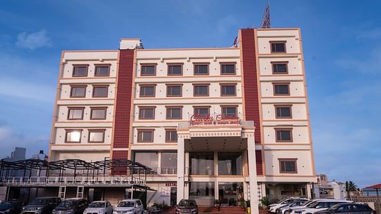 Front view of Clarks Collection Somnath building with facade, multiple floors, parked cars, and a clear blue sky background.