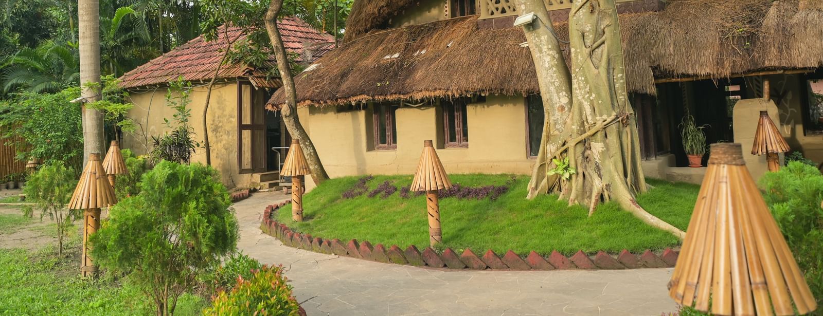 Entrance to Bhoomi Restaurant in Vedic Village Resort featuring a building with mud house style architecture and thatched roof.