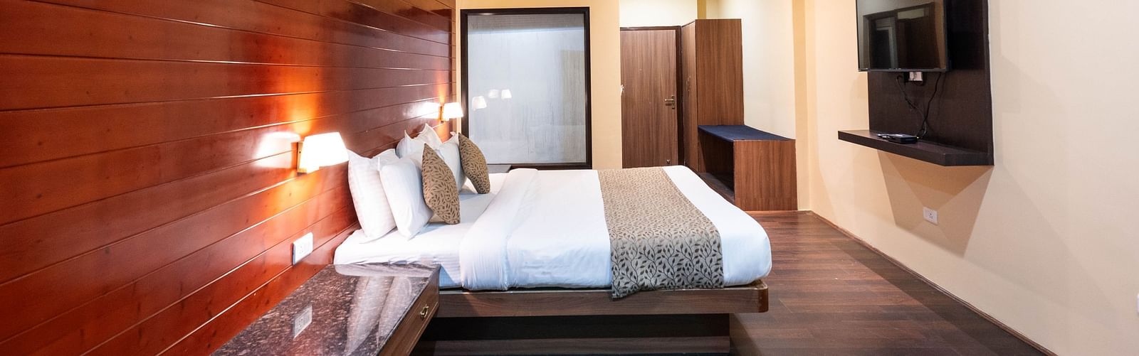Side view of the bedroom featuring a wall-mounted television at Avianna Hungry Jack, Gangtok.
