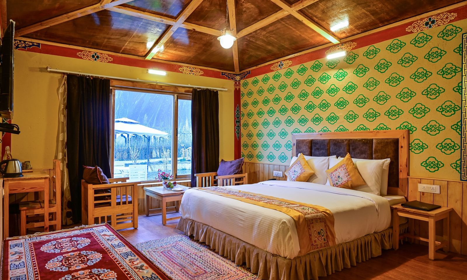 Premium Cottage in White Sands Resort, Ladakh, includes a king size bed, a seating area, and patterned wallpaper.
