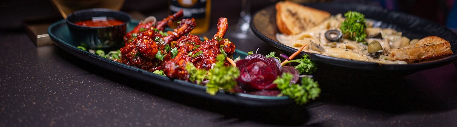 A plate of delicious food accompanied by a beer bottle and a glass of drink, all beautifully arranged with a candle for a cozy atmosphere at hotel moti palace.