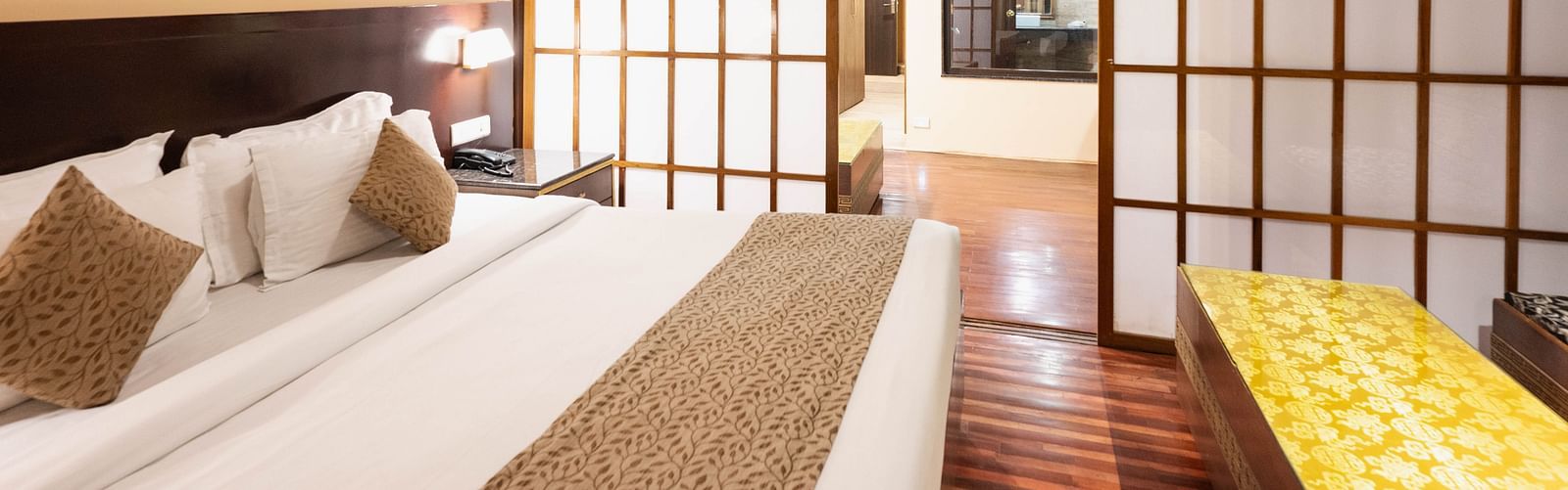 A bedroom with a comfortable bed, sliding doors, and warm lighting leading to another room at Avianna Hungry Jack, Gangtok.