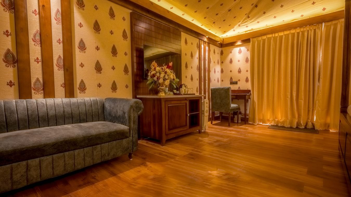 A Premium Duplex text room featuring a  sofa, a cabinet table with flower vase, mirror attached on the wall, and a work desk and chair at The Baagh Ananta Elite, Ranthambore