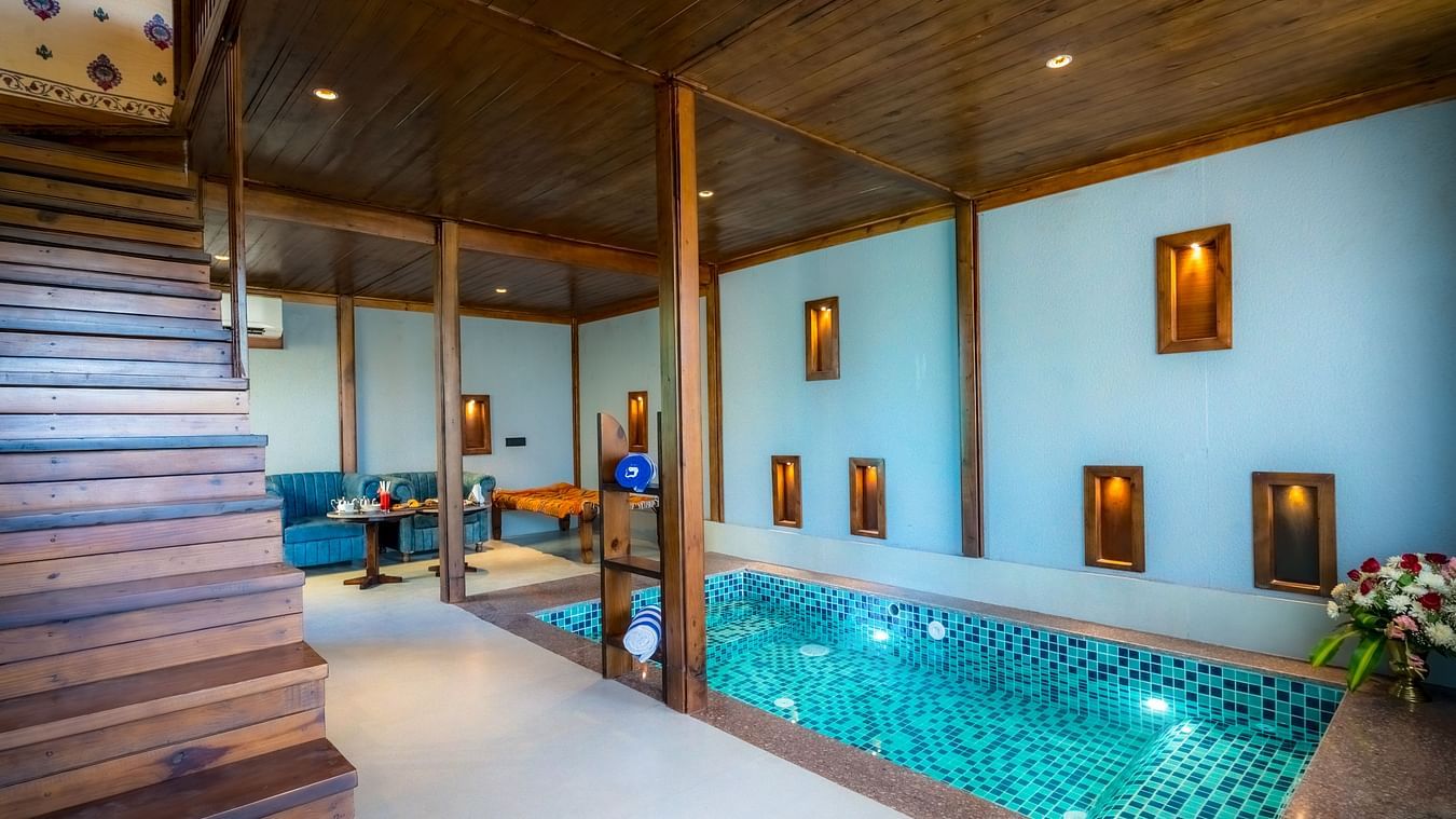 A Premium Duplex Tent featuring  a plunge swimming pool, a sofa set, with centre table, and a flight of wooden stairs at The Baagh Ananta Elite, Ranthambore