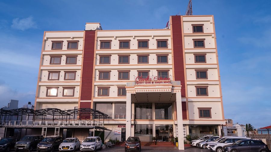 Front view of Clarks Collection Somnath building with facade, multiple floors, parked cars, and a clear blue sky background.