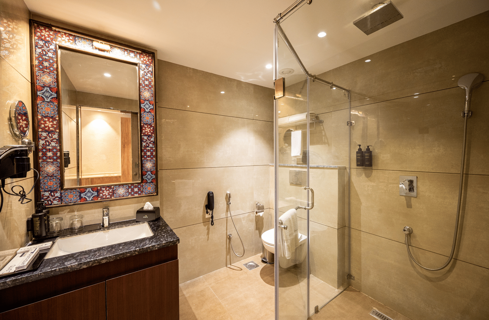 Bathroom of the Standard Room at Essentia Luxury Resort & Spa, Udaipur featuring a vanity next to the shower place separated by a glass panel from the toilet