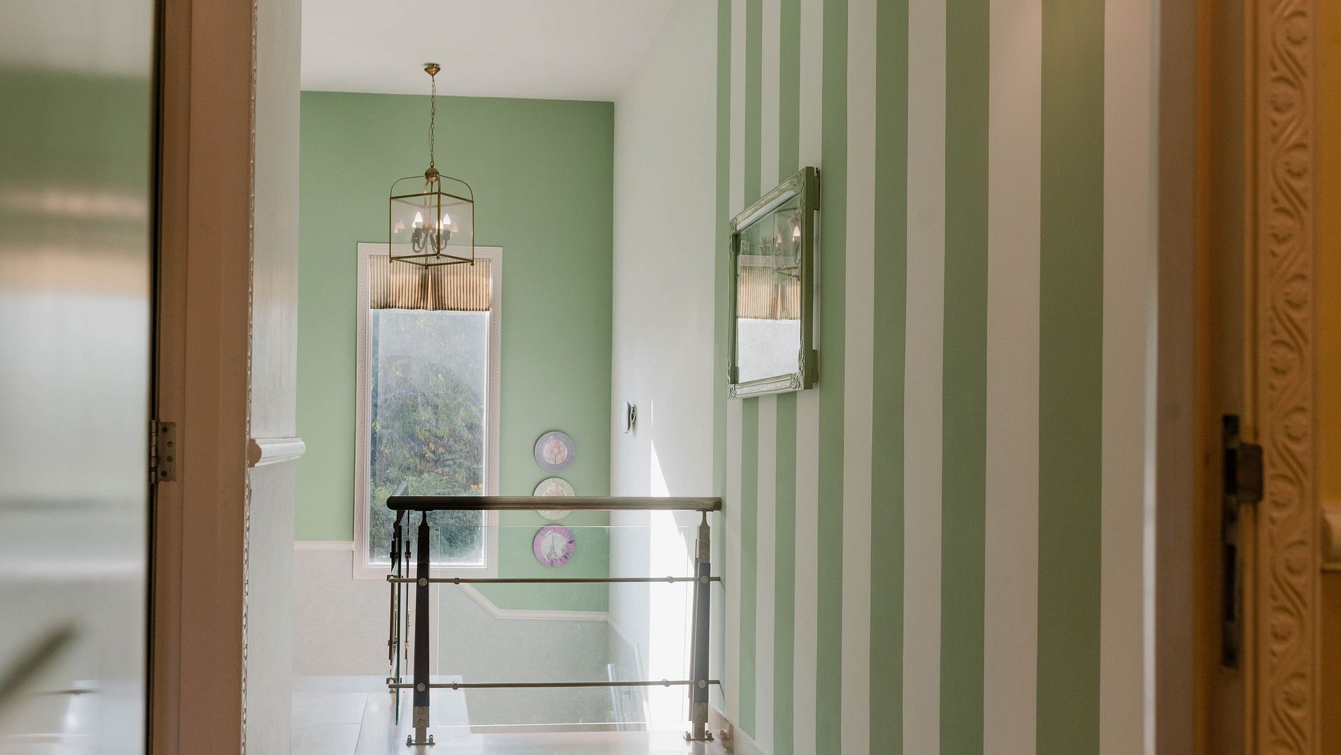 A hallway at Karma Chalets with striped green walls, a hanging light, and doors visible at the end.