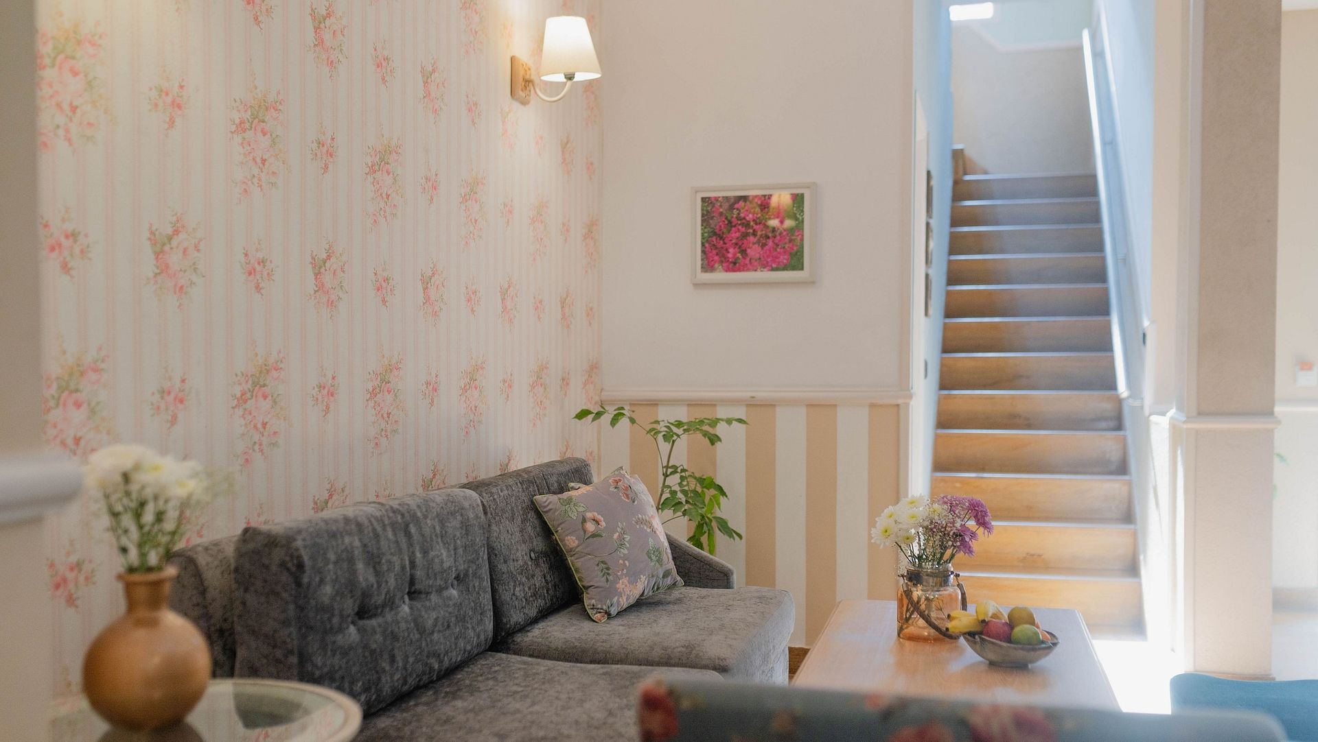 A sitting room at Karma Chalets with a sofa, coffee table, wall art, and stairs in the background.