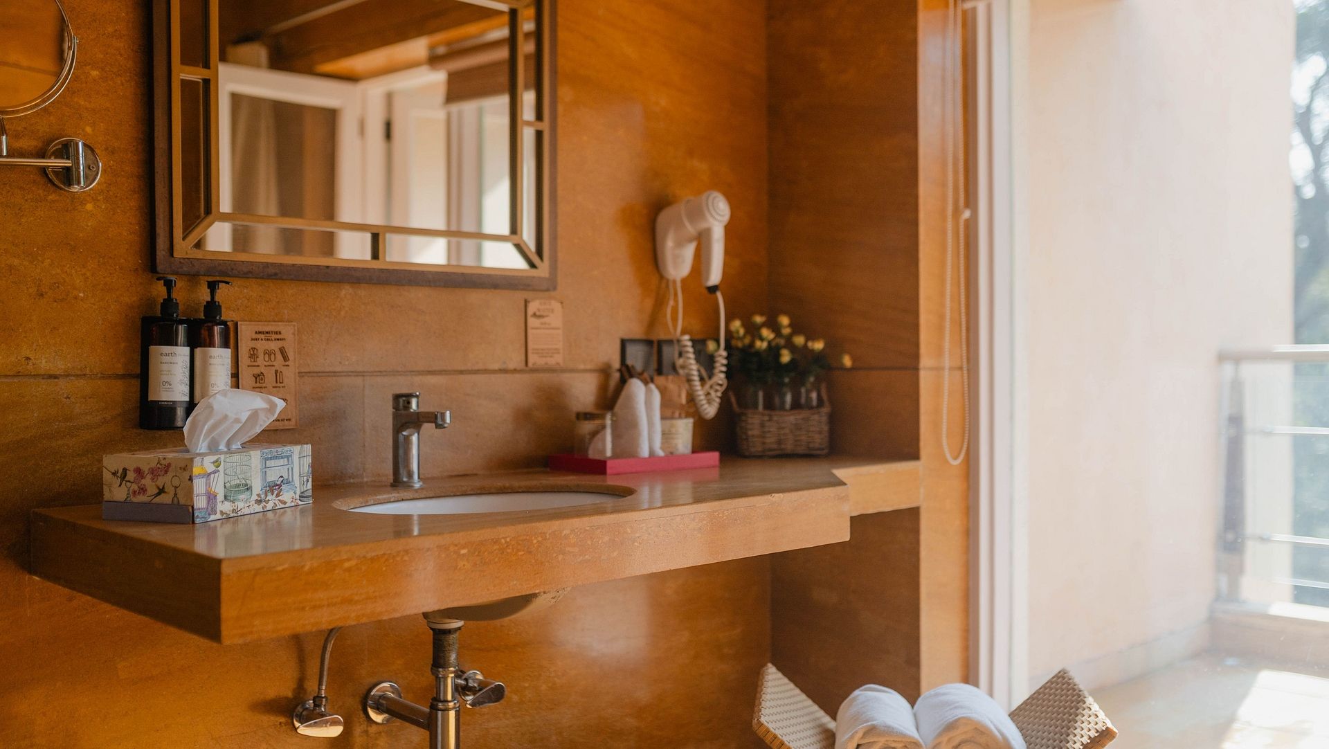 A bathroom at Karma Chalets with a mirror, sink, and toiletry items on a wooden counter.