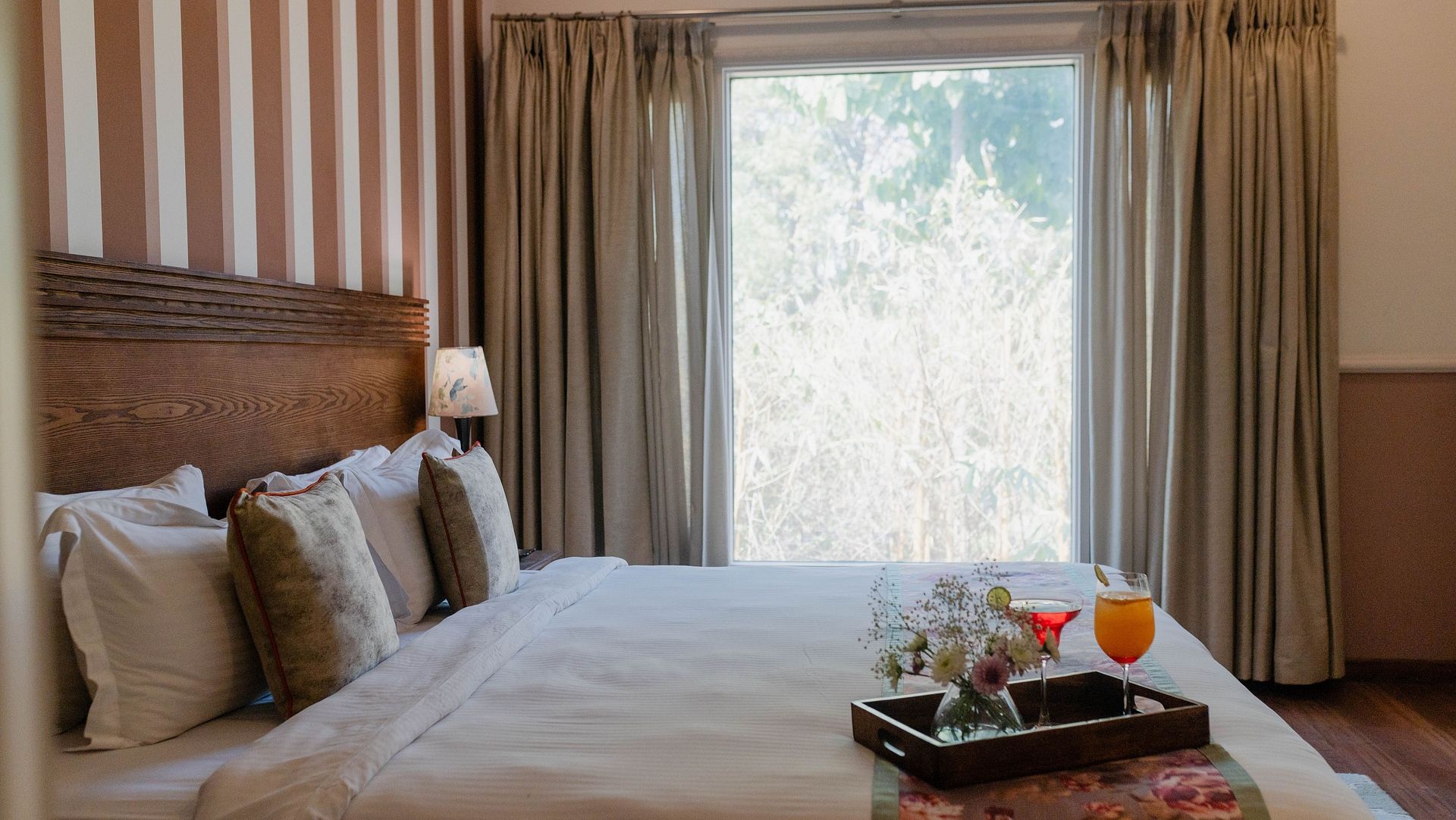 A bedroom at Karma Chalets with a double bed, striped wall panel, and a large window.