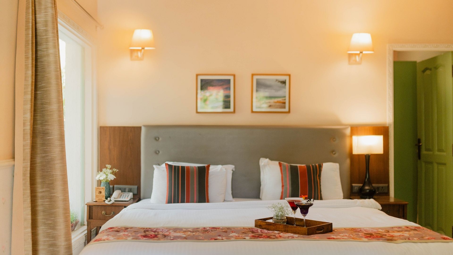 A double bed with wall lamps, framed pictures, and side tables in a room at Karma Chalets.