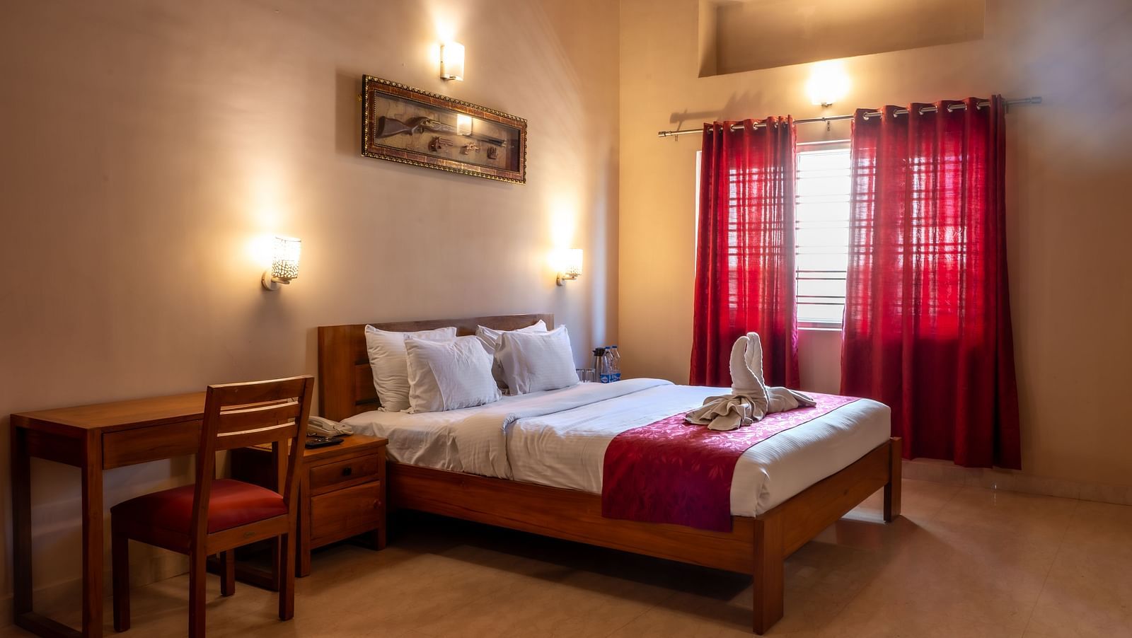 Attic Villa includes a wooden bed with white linens, red curtains, a writing desk, and wall-mounted artwork | Woodstock Resorts, Coorg