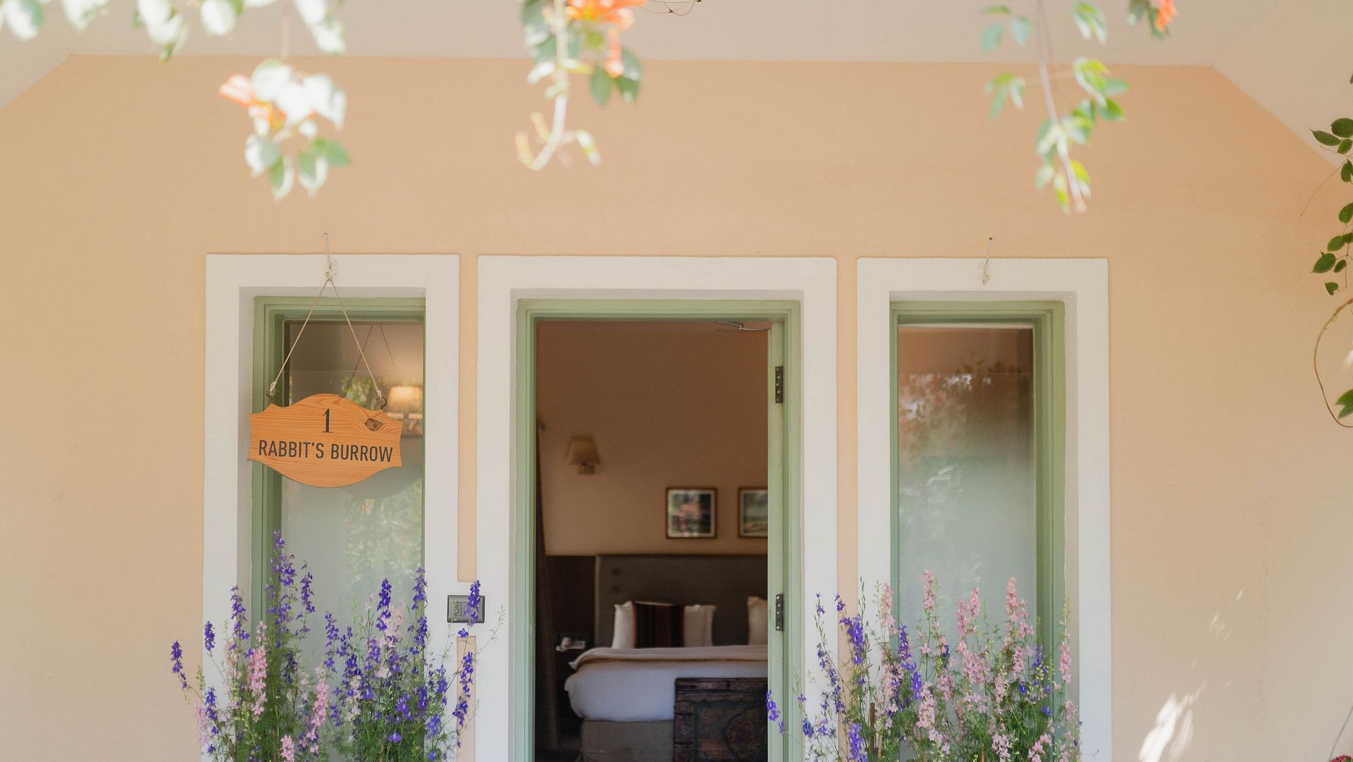 Exterior view of a Karma Chalets unit with two doors, potted plants, and hanging decor.