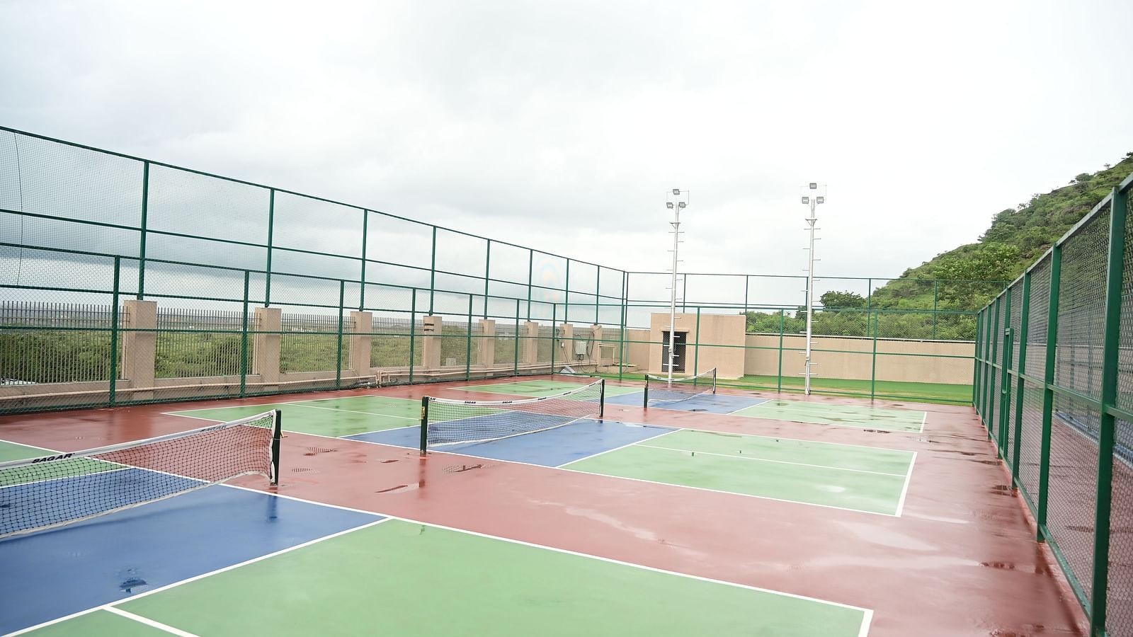 image featuring three tennis courts under a cloudy sky at club charholi, pune