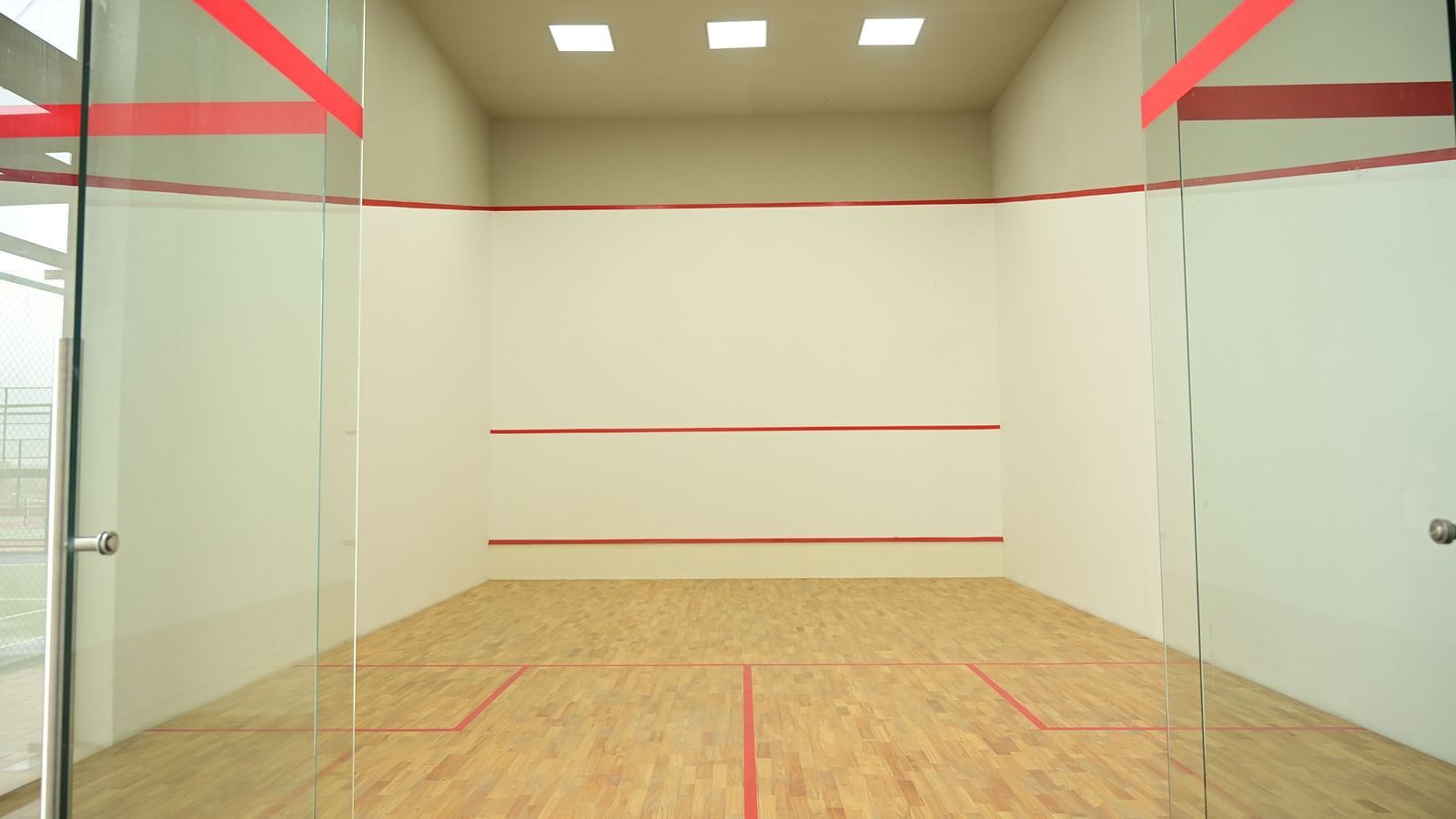 front view image of the squash court with ceiling lights at club charholi, pune