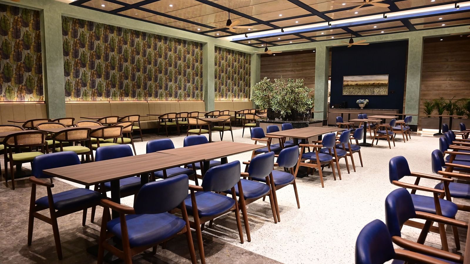 image of several dining tables at with cushioned chairs surrounded around the table at club charholi, pune