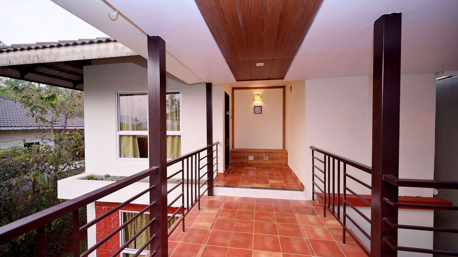 An interior hallway at Forest Escapes Koyna features wooden railings and leads to different areas of the accommodation.