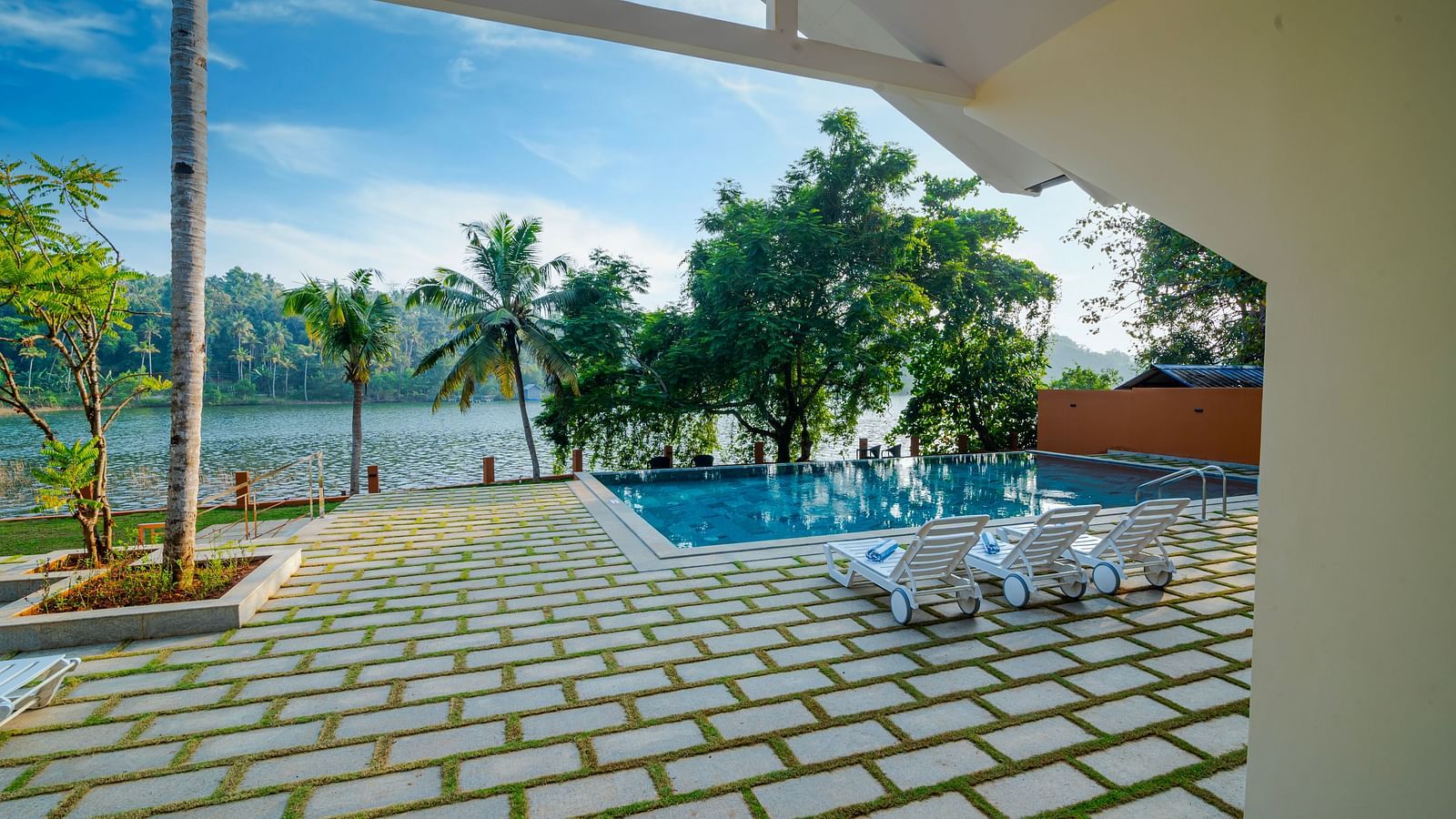 Paved walkway leading to a villa with a pool and a view of the water.