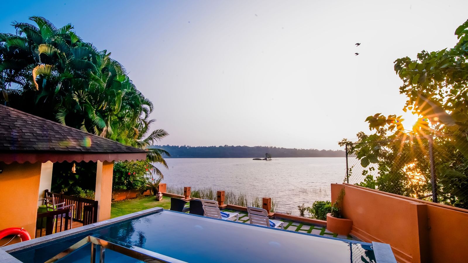 Infinity pool with a stunning sunset view over the water at a resort.
