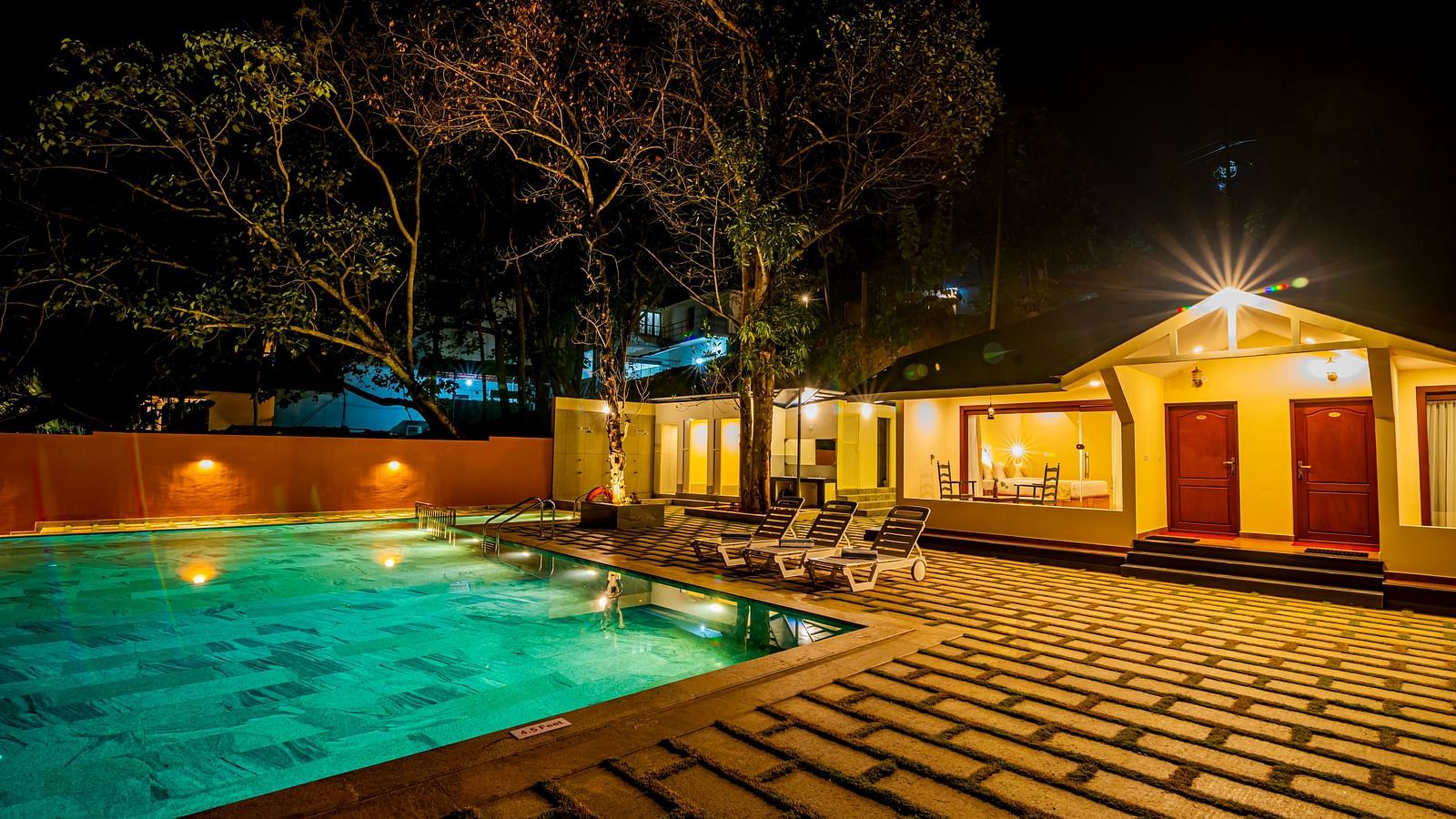 Night view of a resort with a swimming pool and illuminated villas.