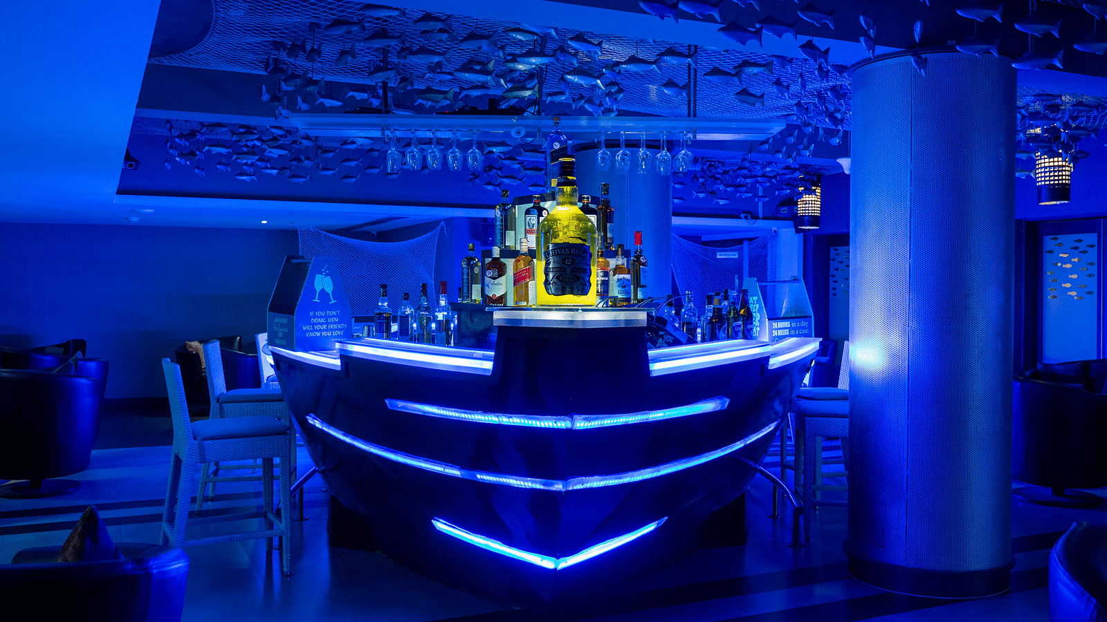 An image of ship themed bar illuminating blue lights at image of an event hall with tables and chairs at Grand Kakinada by GRT Hotels