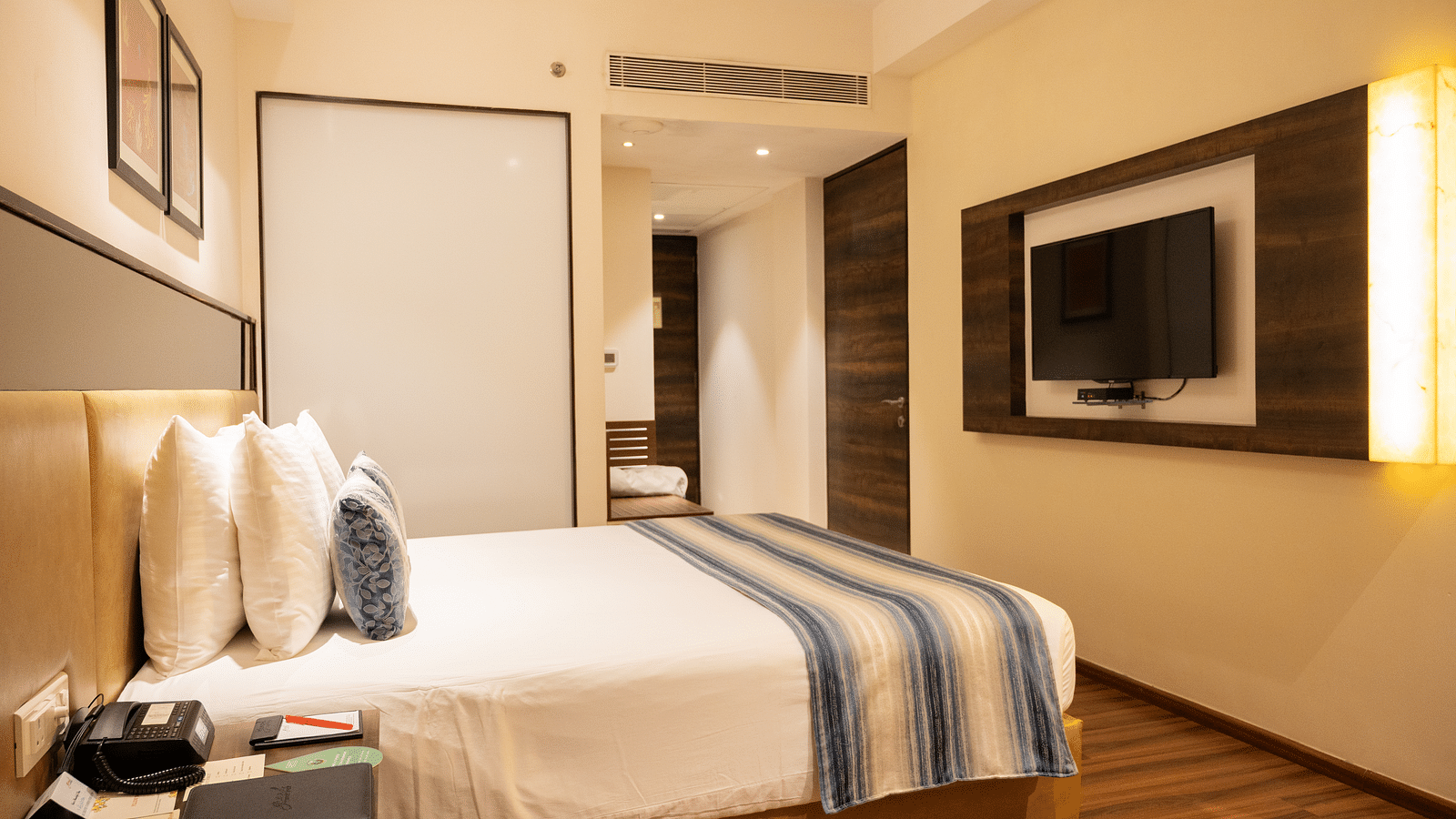 side view of a bedroom with a wall mounted television at Grand Kakinada by GRT Hotels