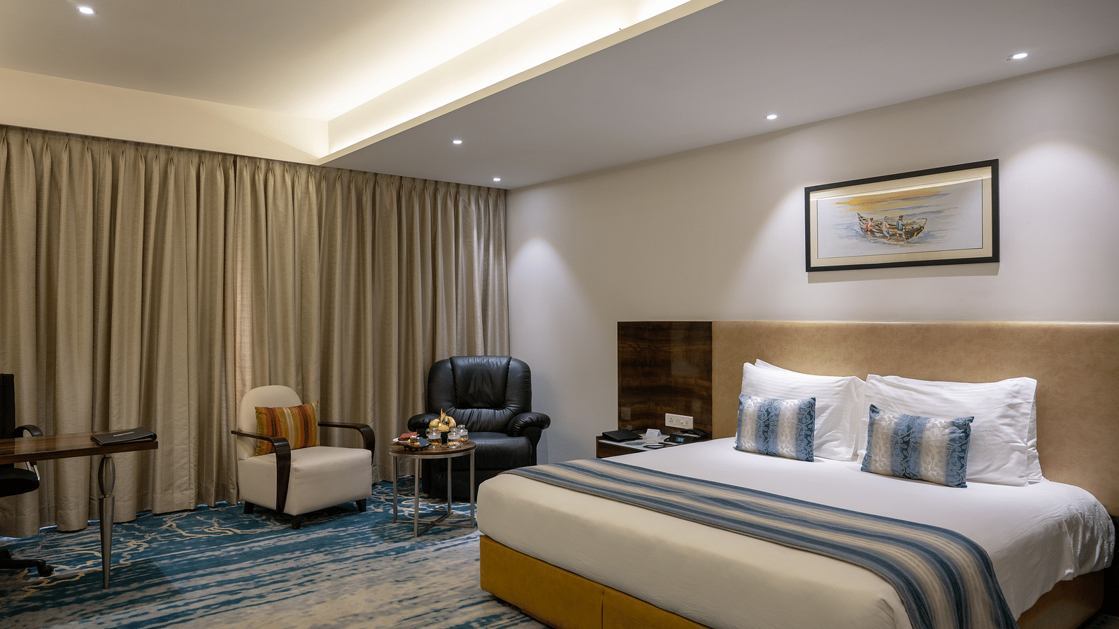 an image of a bedroom with a paining on top of the headboard at Grand Kakinada by GRT Hotels