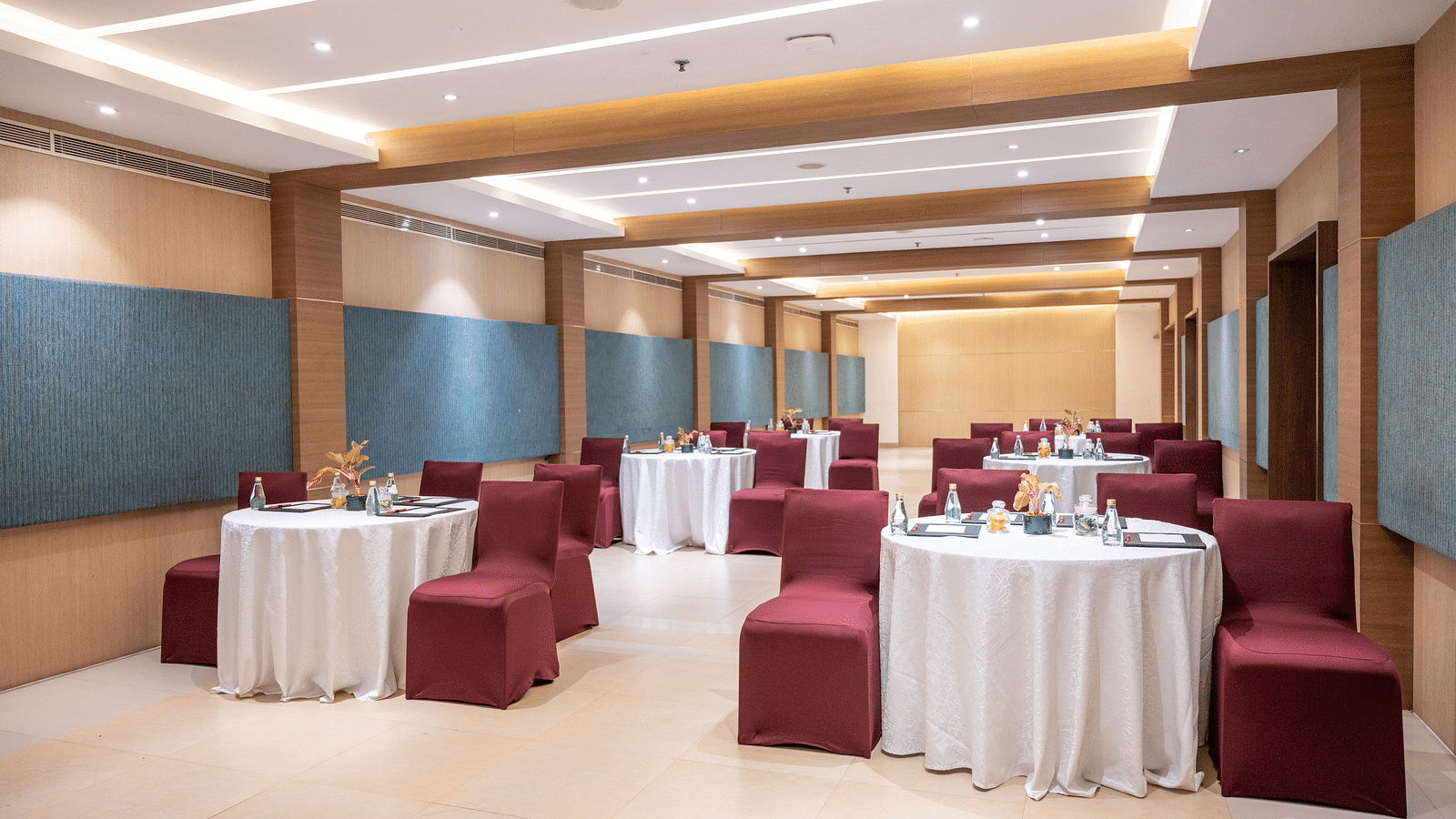 image of an event hall with tables and chairs at Grand Kakinada by GRT Hotels
