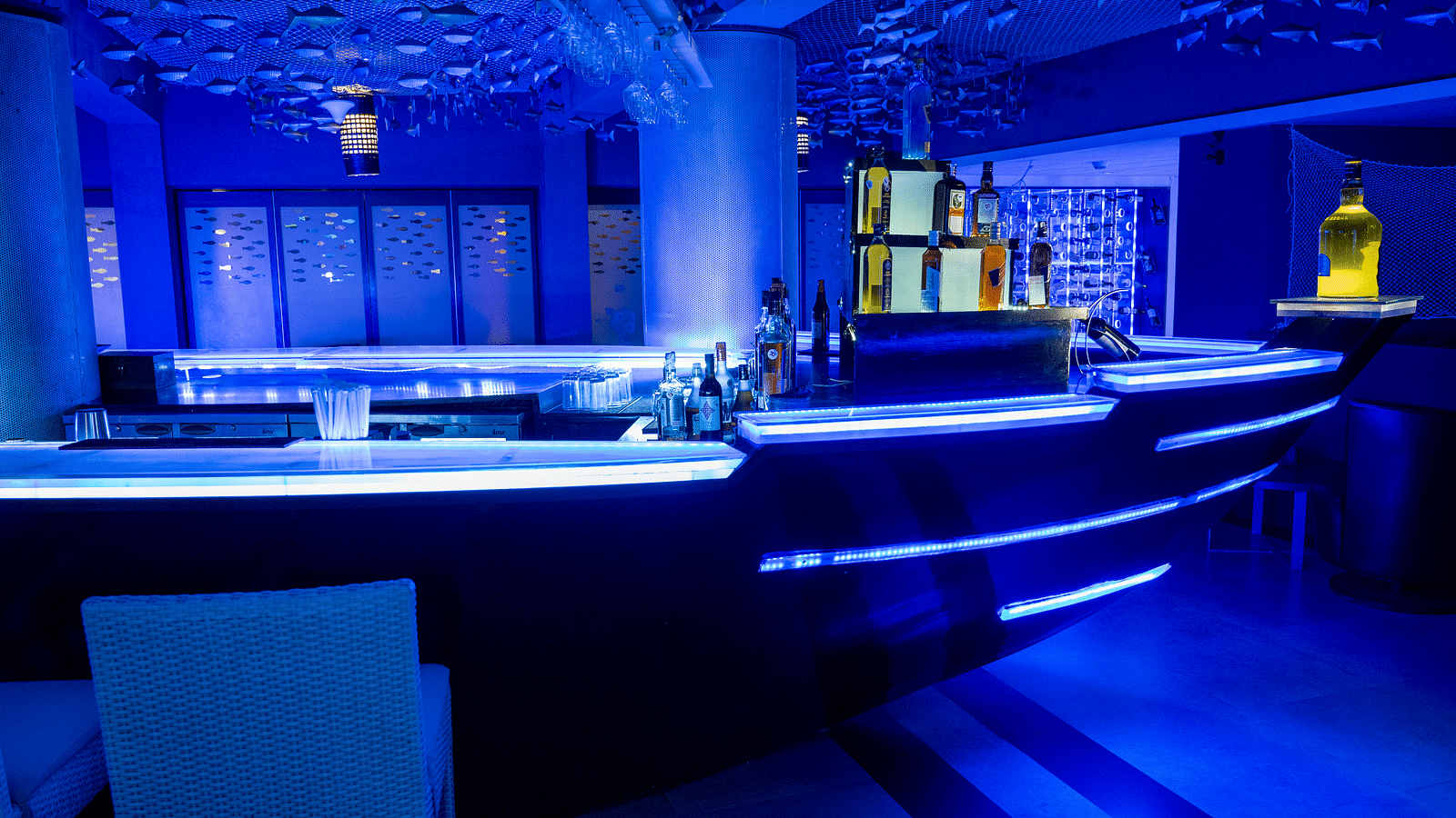 An image of ship shaped bar with metal fishes hanging from the ceiling at image of an event hall with tables and chairs at Grand Kakinada by GRT Hotels
