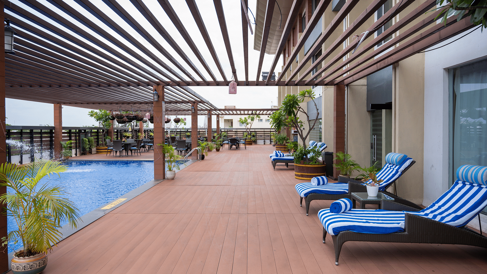 image of sun loungers under the wooden patio beside the pool at Grand Kakinada by GRT Hotels