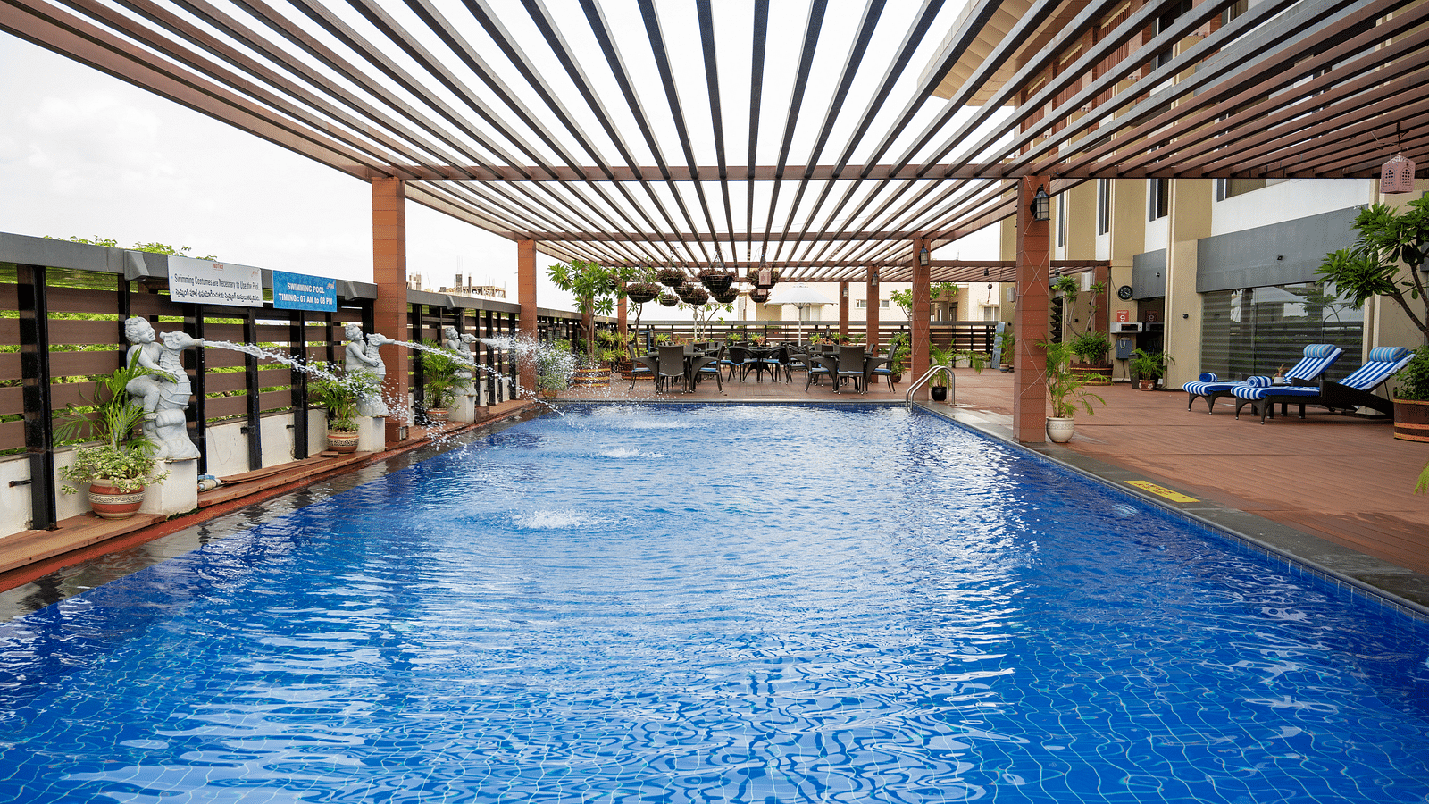 An image of the swimming pool with wooden patio at Grand Kakinada by GRT Hotels