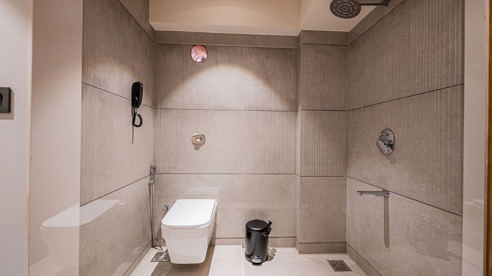 A spacious washroom at Indie Stays Mumbai International Airport, featuring a western toilet and a shower area.