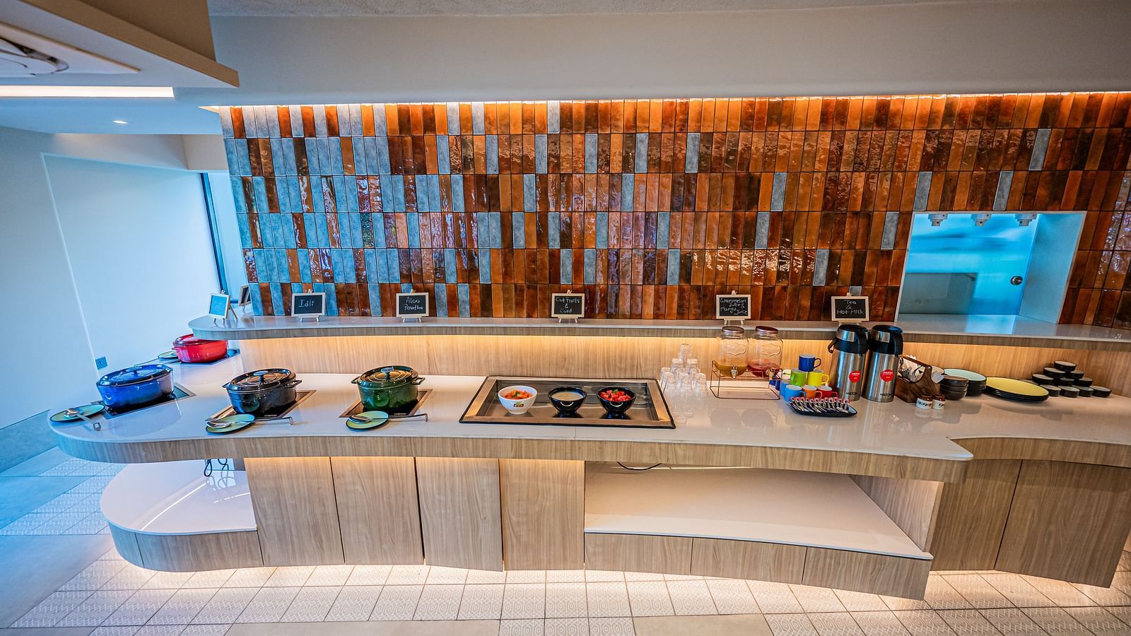 A long view of the kitchen counter at Indie Stays Mumbai International Airport, with essentials neatly placed along it, all under the glow of warm lighting.