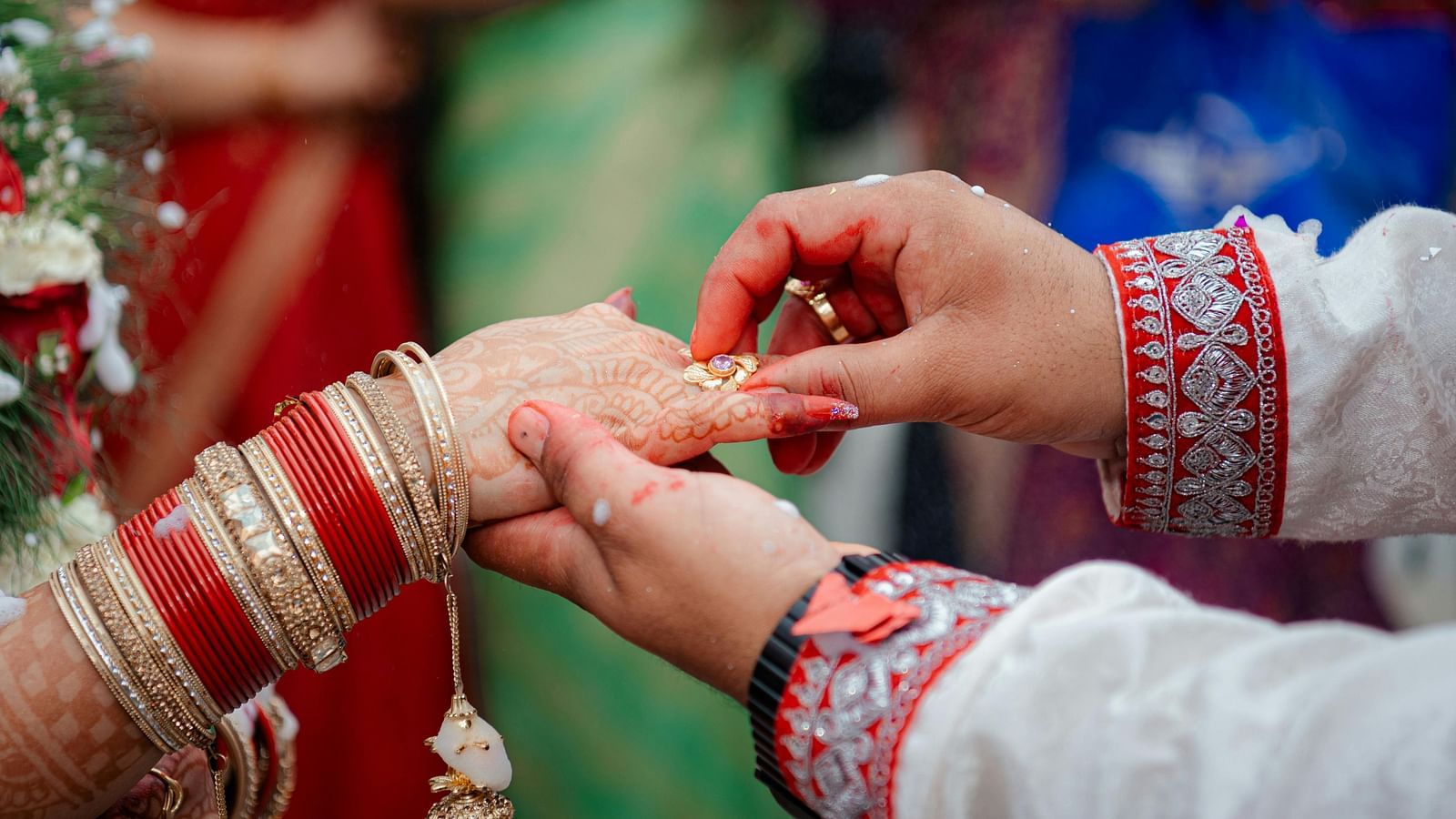 A close-up shot of a groom putting a ring on the bride.