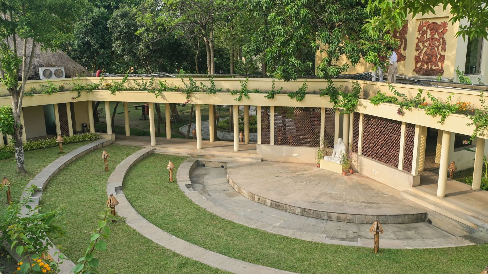 An amphitheatre in Vedic Village Spa Resort featuring a podium and tiered seatings patched by lush green lawns.