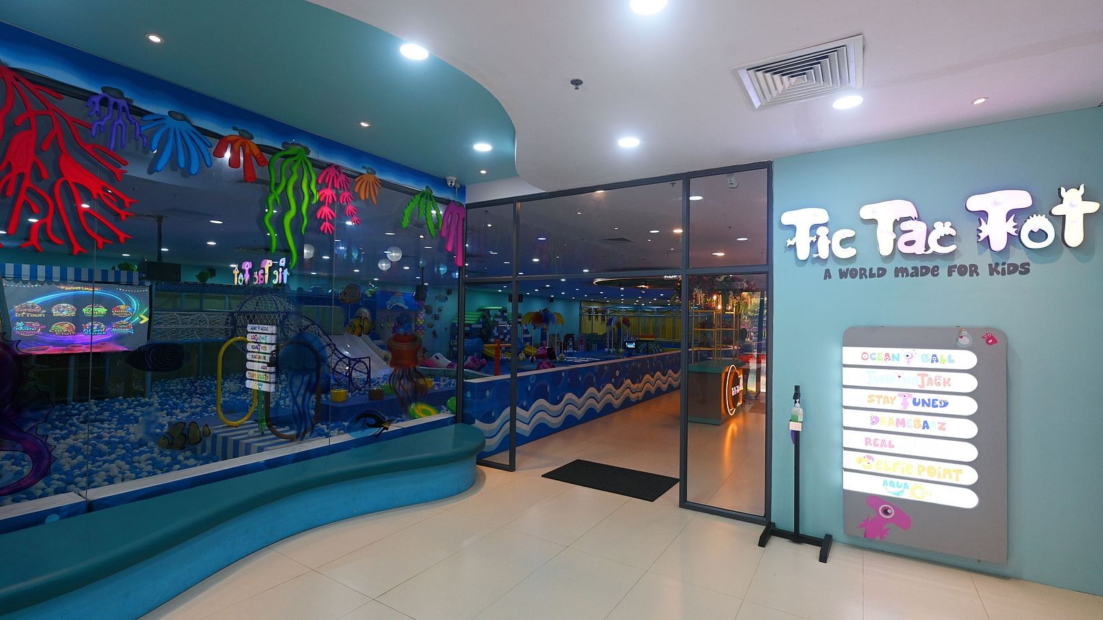 Indoor play area with a Tic Tac Tot sign, a door, and a painted mural on the wall.