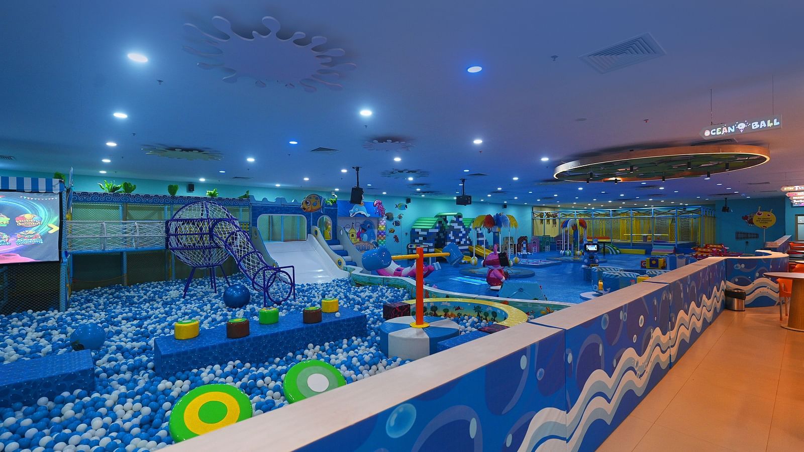 Large indoor play area with a massive ball pit, slides, and climbing structures, under bright lights.