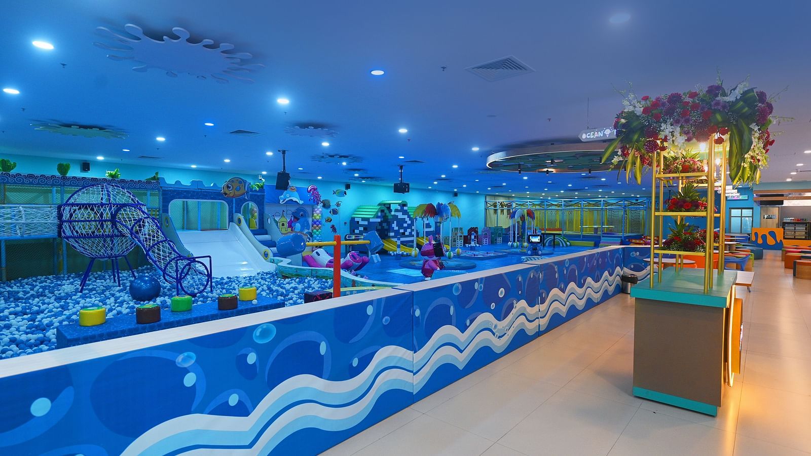 Indoor play area with blue walls, a painted mural, and a long, wavy play structure.