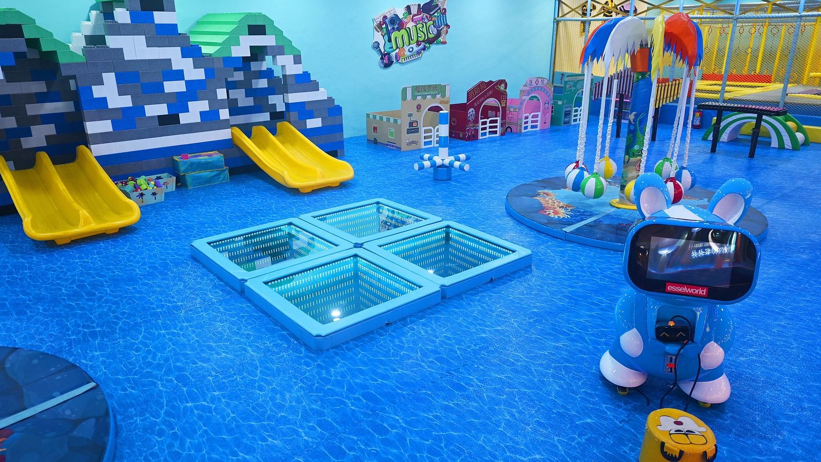 Indoor playground with slides, climbing frames, and a robot toy, featuring a bright and playful design.