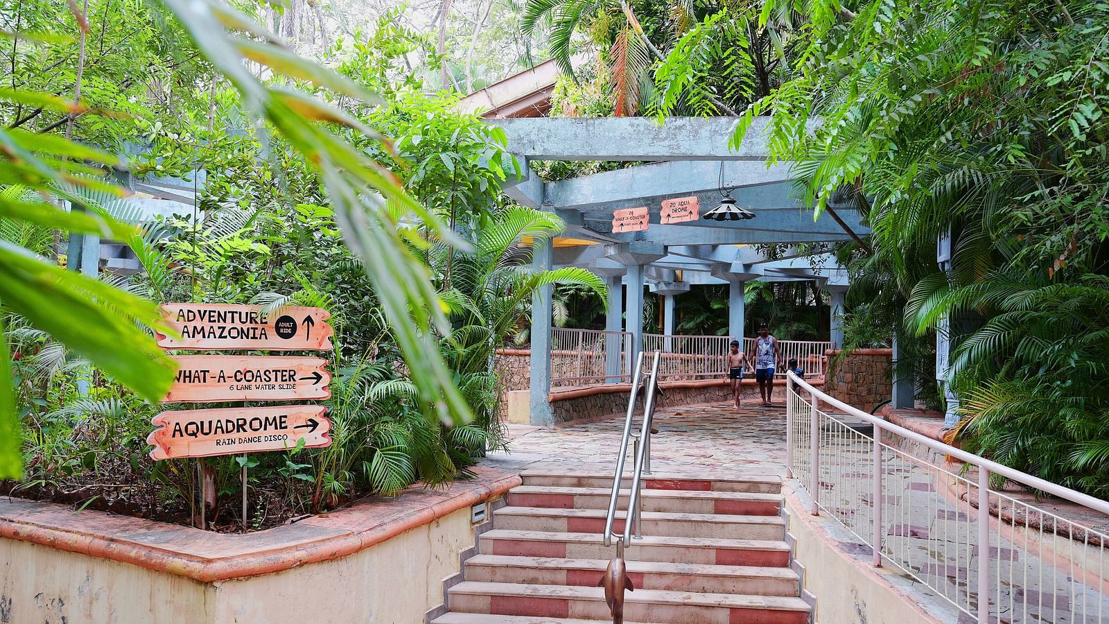 Staircase leading up to a pergola in a lush garden with trees and greenery surrounding it.