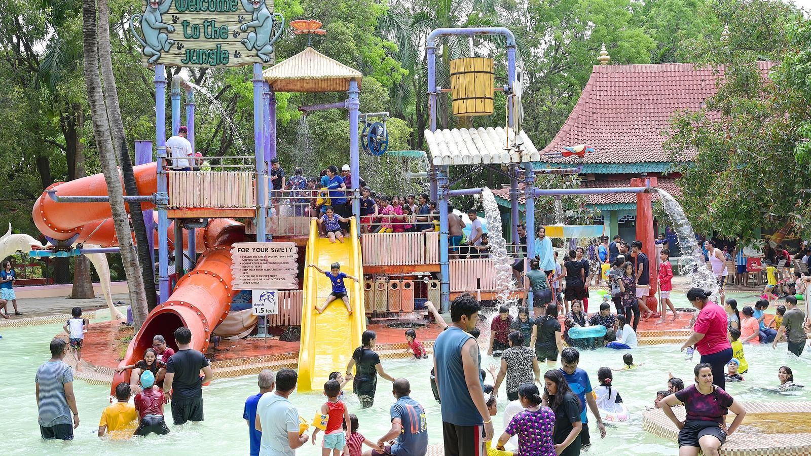 Outdoor playground with slides, climbing frames, and a large crowd of people enjoying the park.