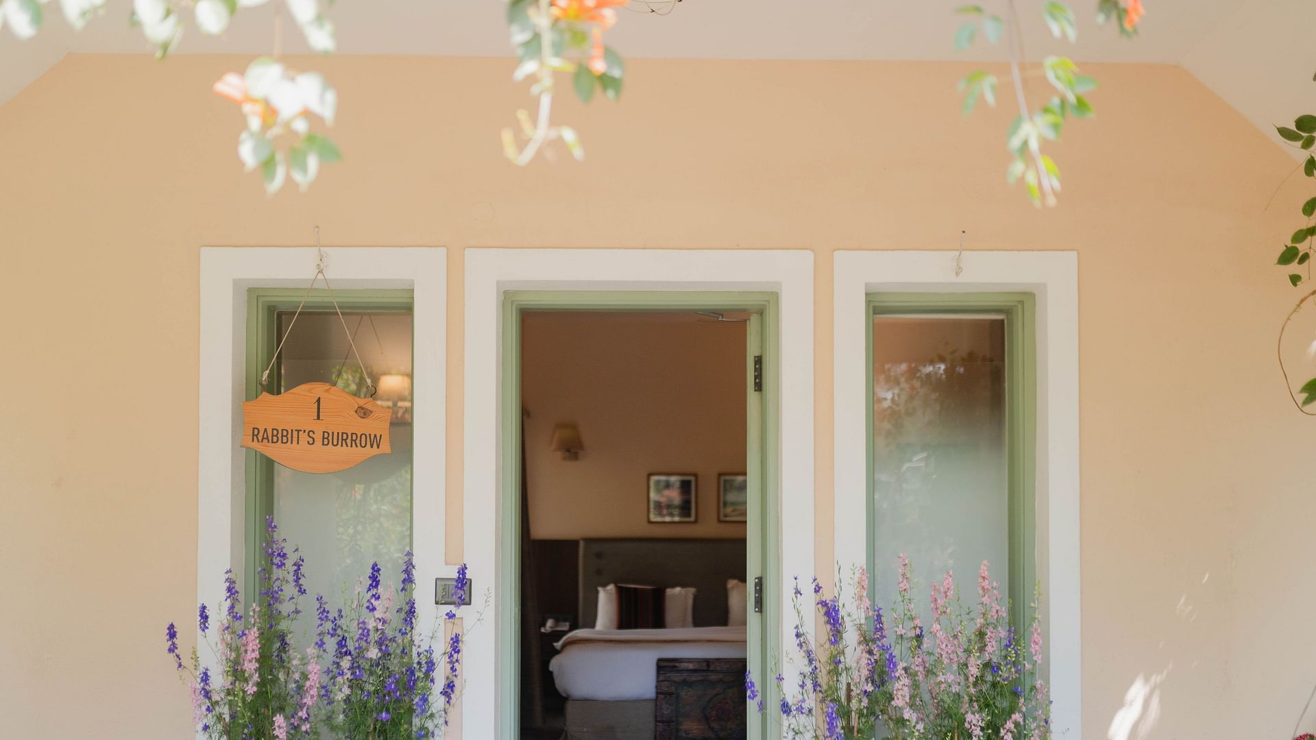 Exterior view of a Karma Chalets unit with two doors, potted plants, and hanging decor.