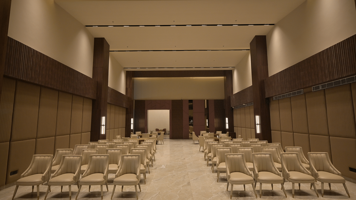 A large meeting room with rows of empty chairs facing a stage area. - Clarks Safari Haridwar