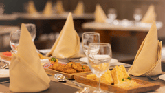 A close-up of a restaurant table set with beige napkins, glassware, and small appetisers at Ananta Express, Katra.