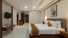 A double bed with a tv opposite it inside Deluxe room - VITS Satyajeet Karad